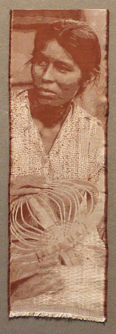 Vertically-oriented banner with photographic woven rendering of a woman weaving a basket in sepia tones.