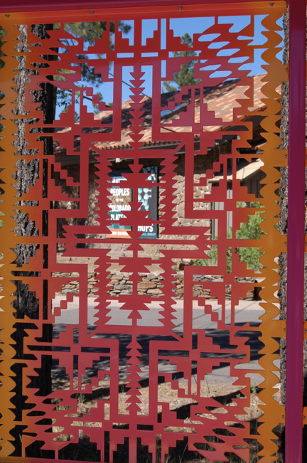 Traditional Navajo tapestry iconography is a wall of bus shelter outside of museum in background