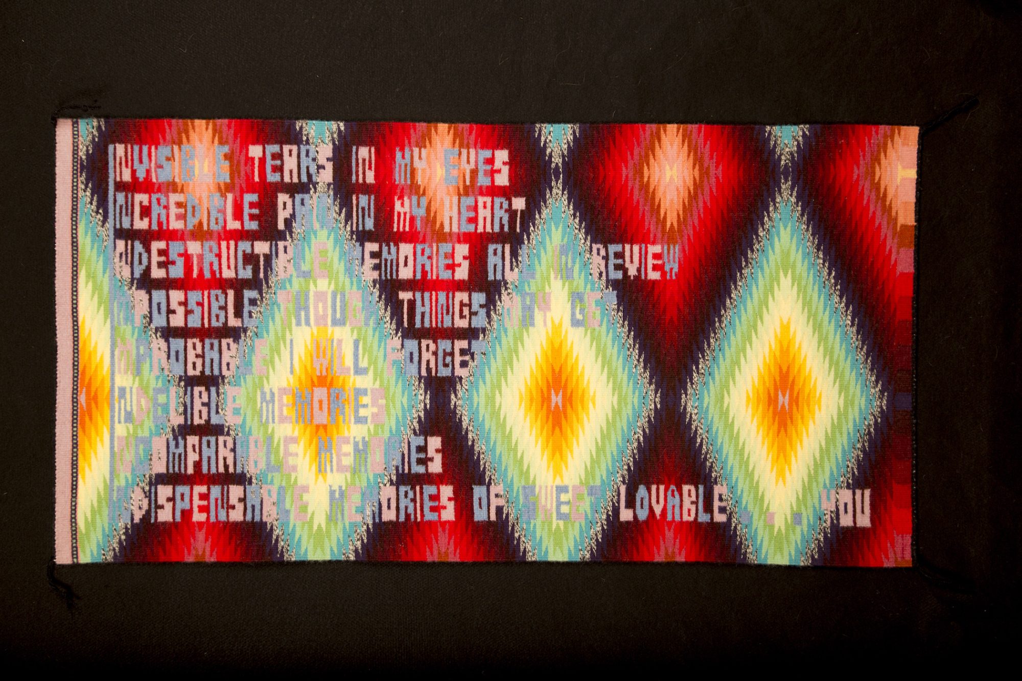 Horizontal tapestry with traditional Navajo iconography has text in background ending with title text "sweet lovable...you"