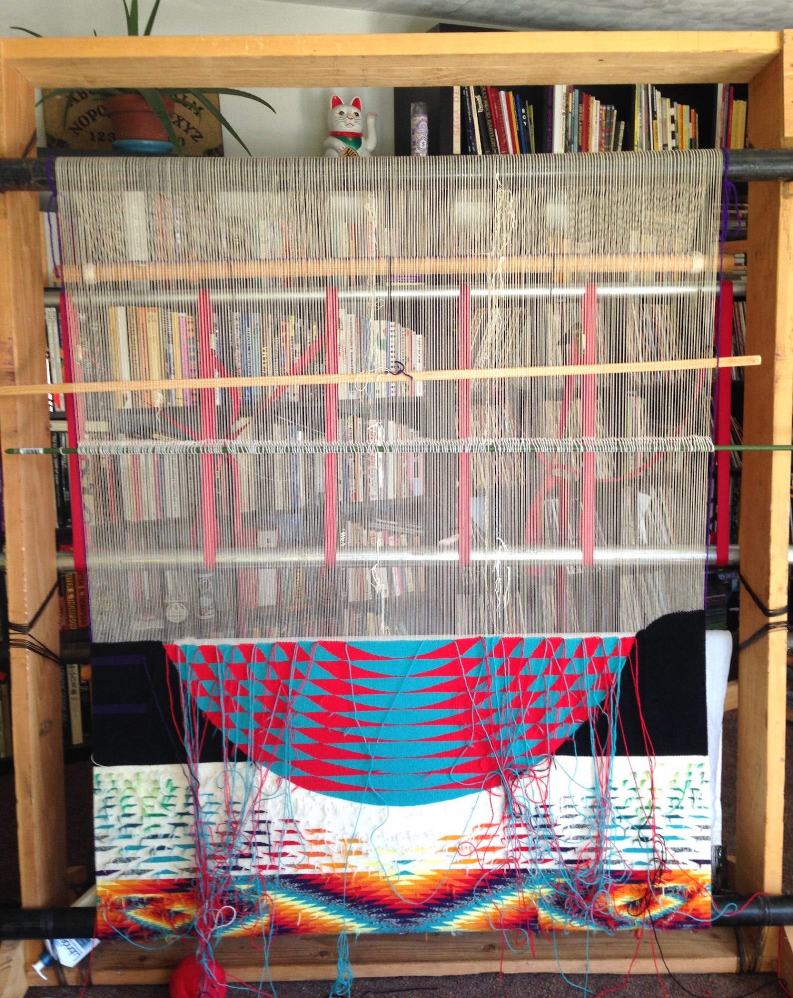 Detail photograph of Melissa Cody's woven tapestry, World Traveler. Red and teal semi-circle are woven on vertical loom.