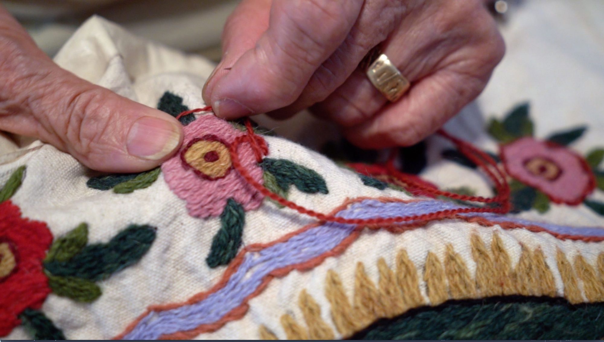 Closeup of hands working on Colcha embroidery
