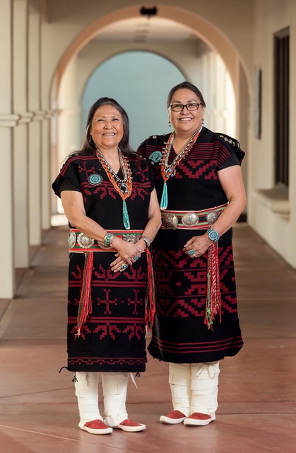 Lynda Teller Pete and Barbara Jean Teller Ornelas stand in front of a long colonnade.